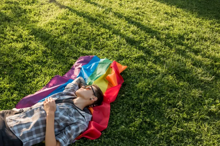 Osoba nieheteronormatywna odpoczywa na łące. Psychoterapia LGBTQ+ w Krakowie. Przylądek Równowagi